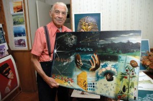 Sol Dember holding art created for Rocketdyne. 