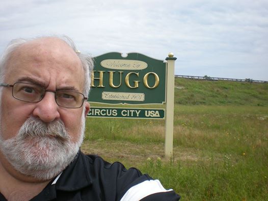 Lou Antonelli poses with sign outside Hugo, Oklahoma.