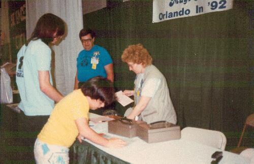 Orlando in '92 bid table at Noreascon 3. Tony Parker (left), Melanie Herz (right), Dan Siclari reading a flyer. Photo by Phylis Brown from Fanac.org site.