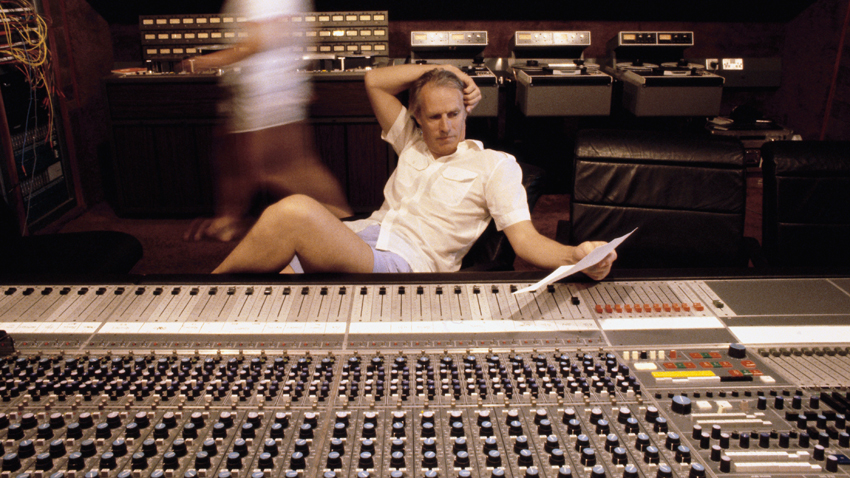 1980s --- Prominent recording producer George Martin sits in a studio next to a sound board. Martin is best known for his work with the Beatles. --- Image by © Martyn Goddard/CORBIS