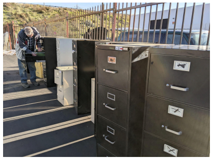 Color photo of 5 three-drawner steel filing cabinets and 1 two-drawer filing cabinet. Gavin Claypool in background.